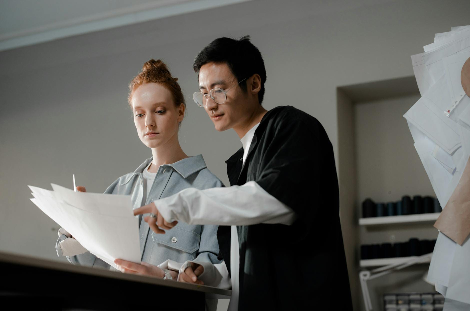 Dwóch projektantów szkicuje wspólnie modowe projekty przy biurku