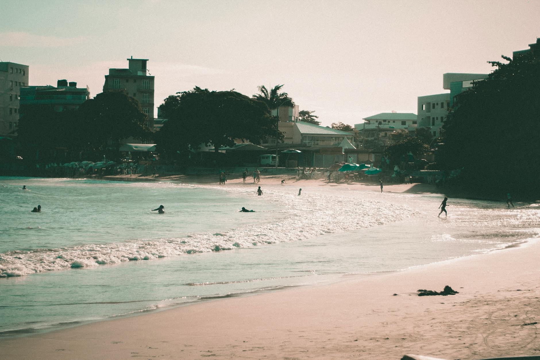 Plaża w Trójmieście z kąpiącymi się ludźmi i panoramą miasta w tle